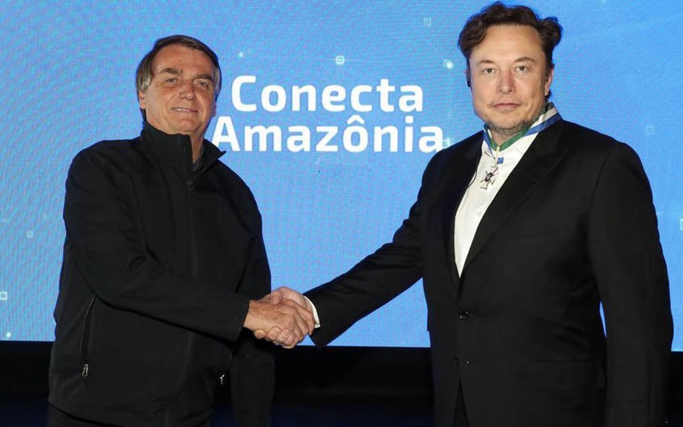 O presente Jair Bolsonaro à esquerda aperta a a mão do empresário Elon Musk à direita