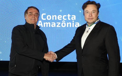 O presente Jair Bolsonaro à esquerda aperta a a mão do empresário Elon Musk à direita
