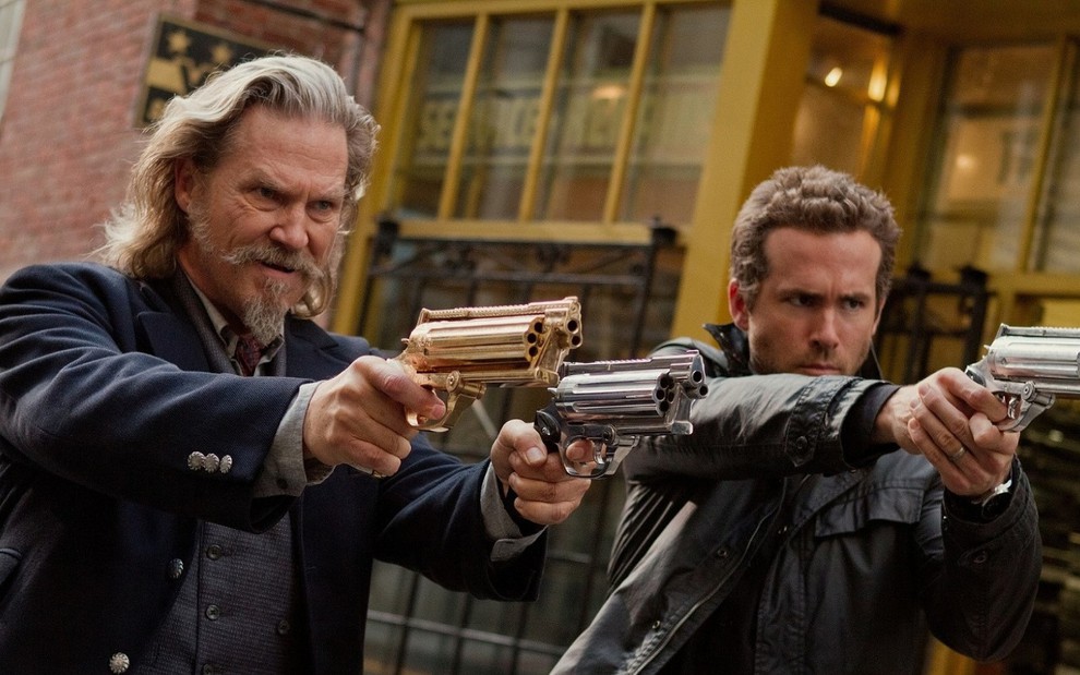 Jeff Bridges veste um paletó e aponta duas armas para a frente (uma dourada e a outra prata); Ryan Reynolds está ao seu lado, vestindo uma jaqueta preta e apontando uma arma para a frente