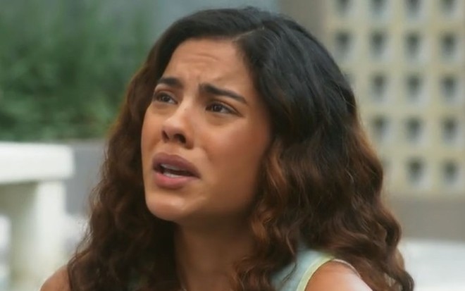 Bella Campos com expressão séria em cena como Jenifer na novela Vai na Fé