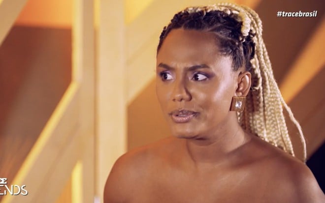 Jéssica Ellen fazendo bico e careta enquanto fala, usando um aplique de tranças no cabelo