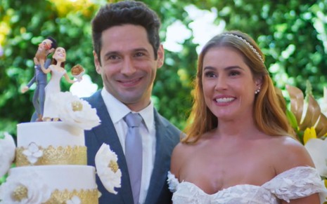 Zezinho (João Baldasserini) e Alexia (Deborah Secco) vestidos de noivos em cena da novela Salve-se Quem Puder