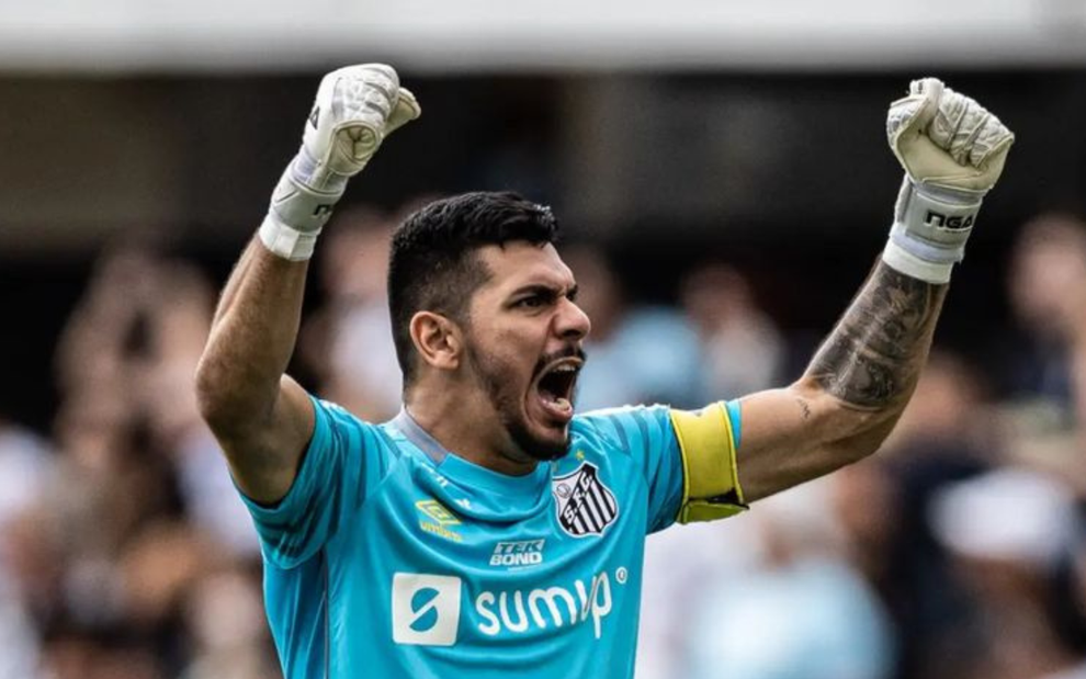 João Paulo, goleiro do Santos, comemora com os dois braços para o alto com uniforme azul