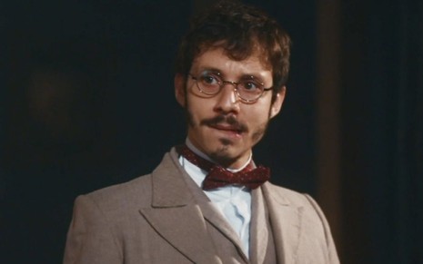 João Pedro Zappa em cena de Nos Tempos do Imperador: caracterizado como Nélio, ator olha com atenção alguém fora do quadro
