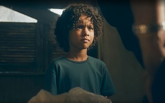 Em cena de Terra e Paixão, Matheus Assis olha para alguém com a expressão séria