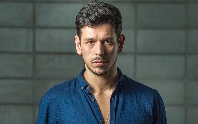 João Vicente de Casto com uma blusa azul e olhar sério em uma gravações de uma produção da Globo
