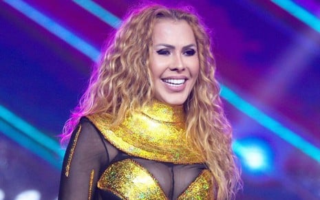 Joelma em foto publicada no Instagram; a cantora está no palco, sorrindo durante um show e veste uma fantasia dourada