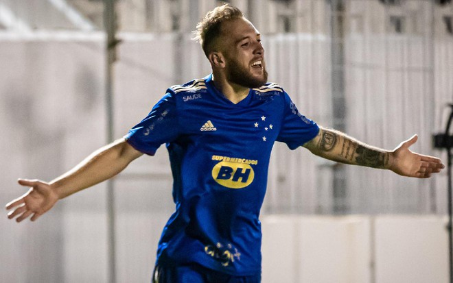 Bruno José com uniforme azul do Cruzeiro corre com os braços abertos para o lado direito