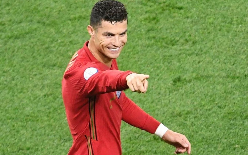 Cristiano Ronaldo com a camisa vermelha de Portugal com o braço direito levantado em partida na Eurocopa