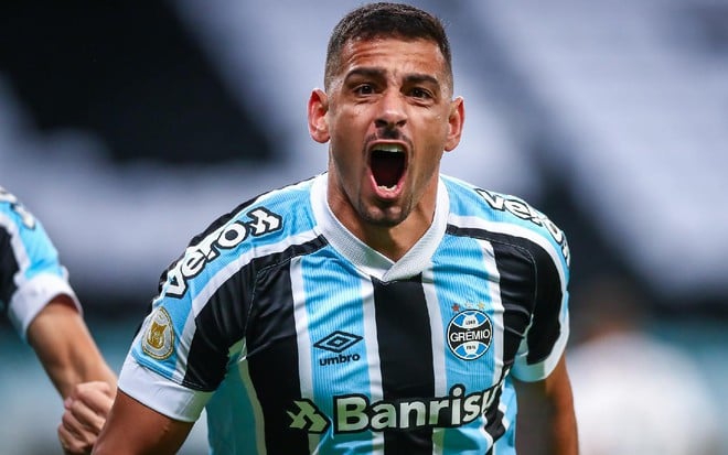 Diego Souza com a camisa azul, preta e branca do Grêmio corre com a boca aberta em celebração de gol em partida