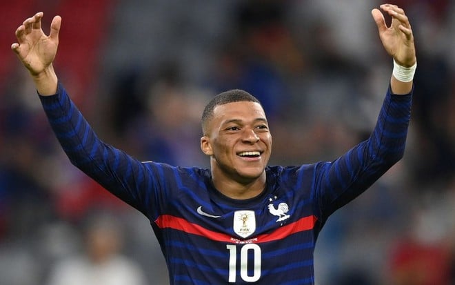 Sorridente, Mbappé ergue os braços para comemorar gol da França