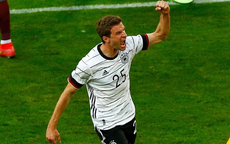 Thomas Müller com a camisa branca da Alemanha com a mãe esquerda levantada e punho cerrado e gritando em campo em jogo da Alemanha na Eurocopa