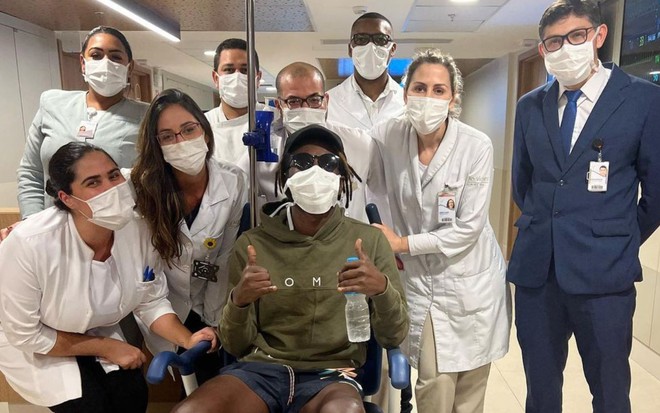 Foto do ator Jonathan Azevedo em uma cadeira de rodas com uma equipe médica em sua volta