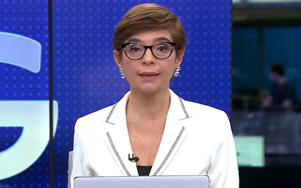 Renata Lo Prete usa um blazer branco enquanto apresenta o Jornal da Globo