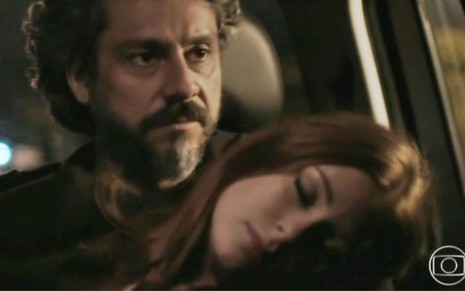 Maria Isis (Marina Ruy Barbosa) está desmaiada no colo de José Alfredo (Alexandre Nero) dentro de carro em cena de Império
