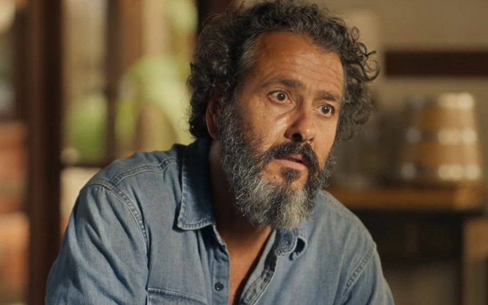 O ator Marcos Palmeira como José Leôncio em Pantanal; ele está sentado olhando para frente com cara de impressionado