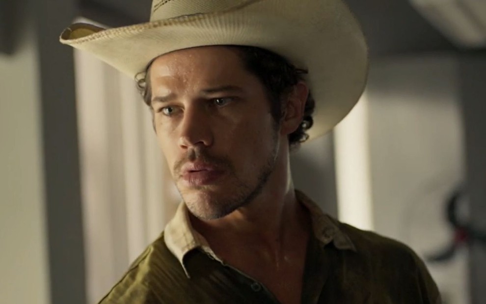 José Loreto está com expressão séria e usa chapéu de peão em cena como Tadeu na novela Pantanal