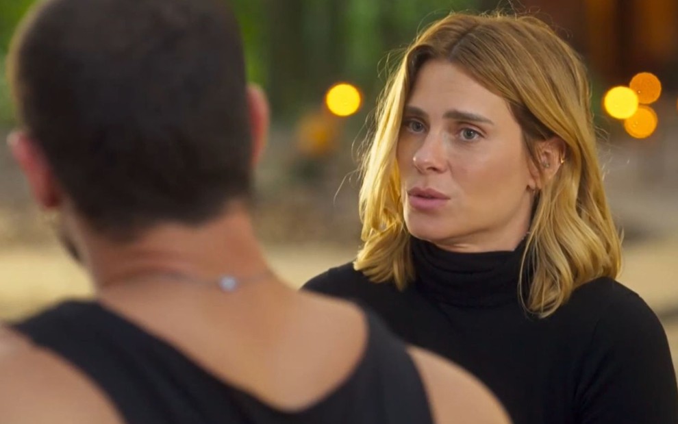 De costas na imagem, Lui Lorenzo (José Loreto) conversa com Lumiar (Carolina Dieckmann) em cena da novela Vai na Fé