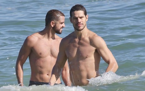 Sem camisa, José Loreto está no mar forçando os músculos ao lado de Rodrigo Simas