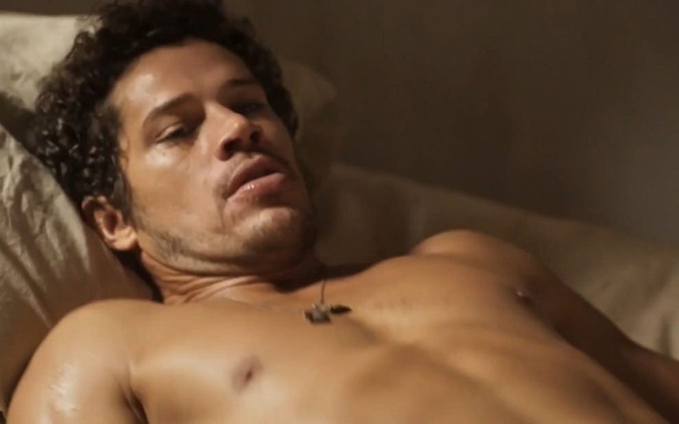 José Loreto está deitado e sem camisa em cena como Tadeu na novela Pantanal