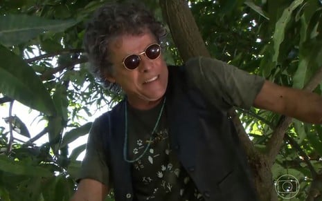 O ator José Mayer como Augusto César em A Favorita; ele está de óculos de sol, virado para o lado, em cima de uma árvore
