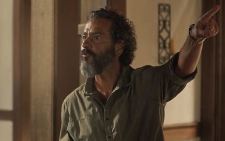 O ator Marcos Palmeira como José Leôncio em Pantanal; ele está em pé, conversando e apontando com o indicador esquerdo para cima