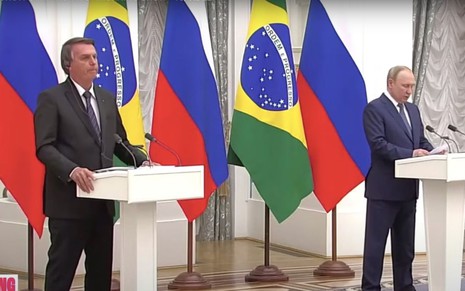 Foto do presidente do Brasil, Jair Bolsonaro (à esquerda), e o presidente da Rússia, Vladimir Putin (à direita), falando em púlpitos em coletiva de imprensa na Rússia