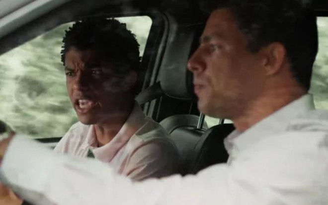 Christian (Cauã Reymond) e Ravi (Juan Paiva) estão dentro de carro, alterados, em cena de Um Lugar ao Sol