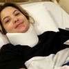 A atriz Júlia Gomes deitada em um leito de hospital com o pescoço imobilizado
