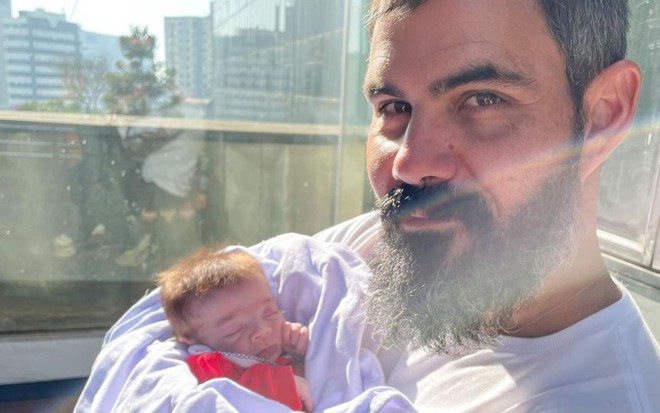 Imagem de Juliano Cazarré com a filha Maria Guilhermina no colo