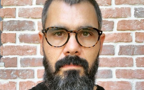 Juliano Cazarré está de óculos e barba