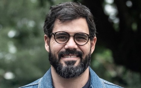 Juliano Cazarré de óculos em paisagem florestal