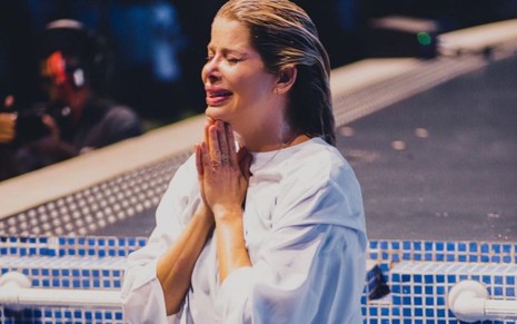 Agora evangélica, Karina Bacchi em piscina; de olhos fechados, atriz une as mãos em símbolo de fé