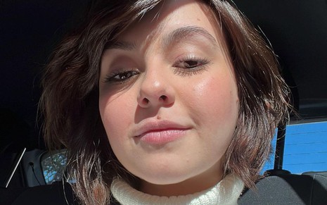 Klara Castanho em selfie; ela usa uma blusa branca de gola alta
