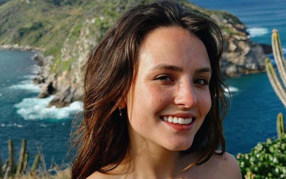 Larissa Manoela está sorrindo, de biquíni, com paisagem natural ao fundo