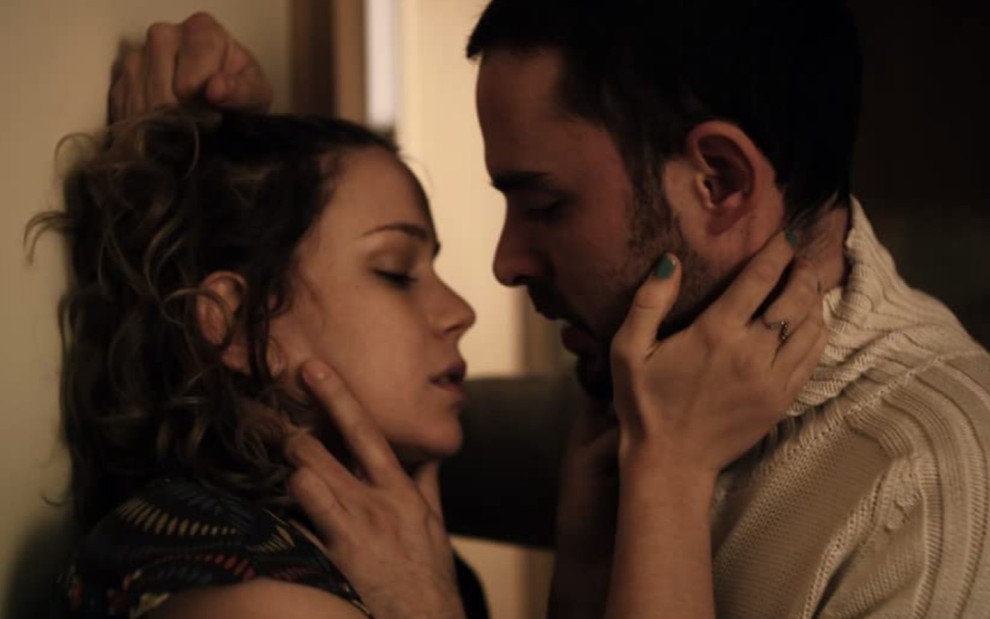 Leandra Leal e Manolo Cardona, com a mão um no rosto do outro, se inclinam para um beijo