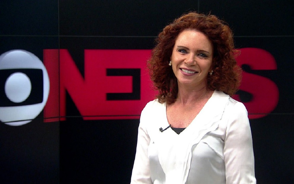 Leilane Neubarth nos estúdios da GloboNews, no Rio de Janeiro: ela usa uma blusa branca, sorri de forma simpatica e atrás está o logotipo do canal de notícias da Globo