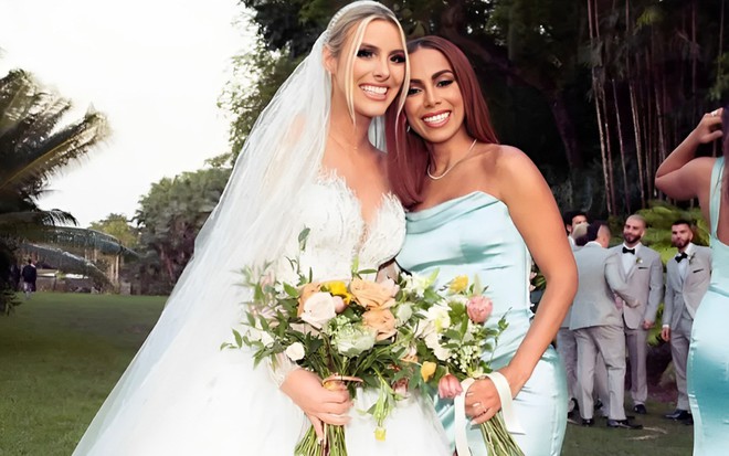 Vestida de noiva, Lele Pons sorri e abraça Anitta em foto de seu casamento