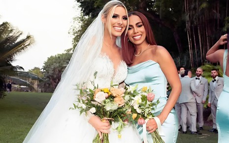 Vestida de noiva, Lele Pons sorri e abraça Anitta em foto de seu casamento