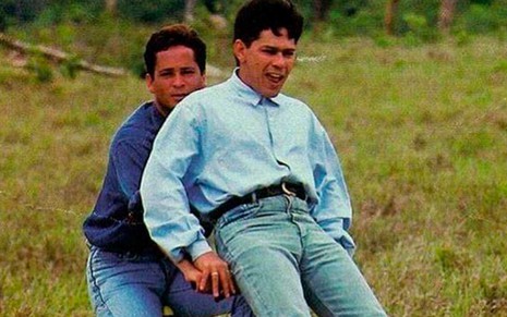 O cantor Leonardo pilota uma bicicleta em um pasto com o irmão Leandro sentado no guidão