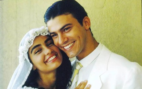 Leonardo Vieira vestido de terno branco e gravata abraça Patrícia França, vestida de noiva, em cena de Renascer