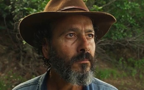 O ator Marcos Palmeira como José Leôncio em Pantanal; ele está de chapéu, em meio à natureza, olhando levemente para o lado