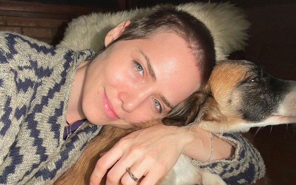 De cabelos raspados, Leticia Colin abraça um cachorro em foto publicada no Instagram