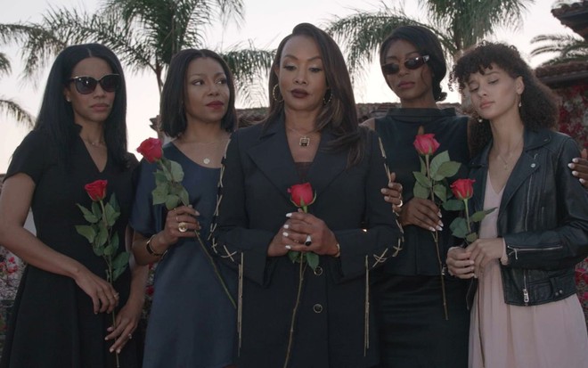 Atrizes da série de filmes Família Jones, vestidas de preto, em cena de funeral