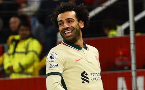 Mohamed Salah, do Liverpool, vestindo uniforme bege com detalhes verde, sorrindo e comemorando gol
