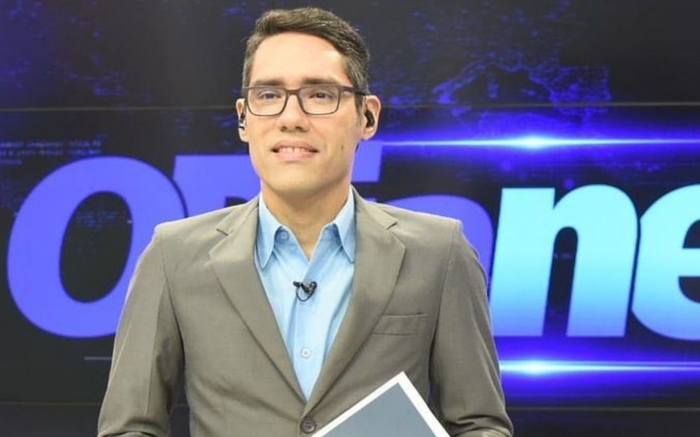 Lívio Galeno usa terno e está em frente ao telão do programa O Dia News