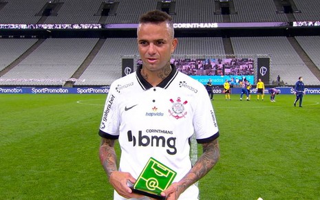 O jogador Luan Guilherme, suado, segura o Troféu Internet com a camisa do Corinthians