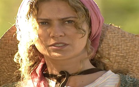A atriz Patricia Pillar como Luana em O Rei do Gado; ela está usando um lenço e olhando para frente, com cara de observadora