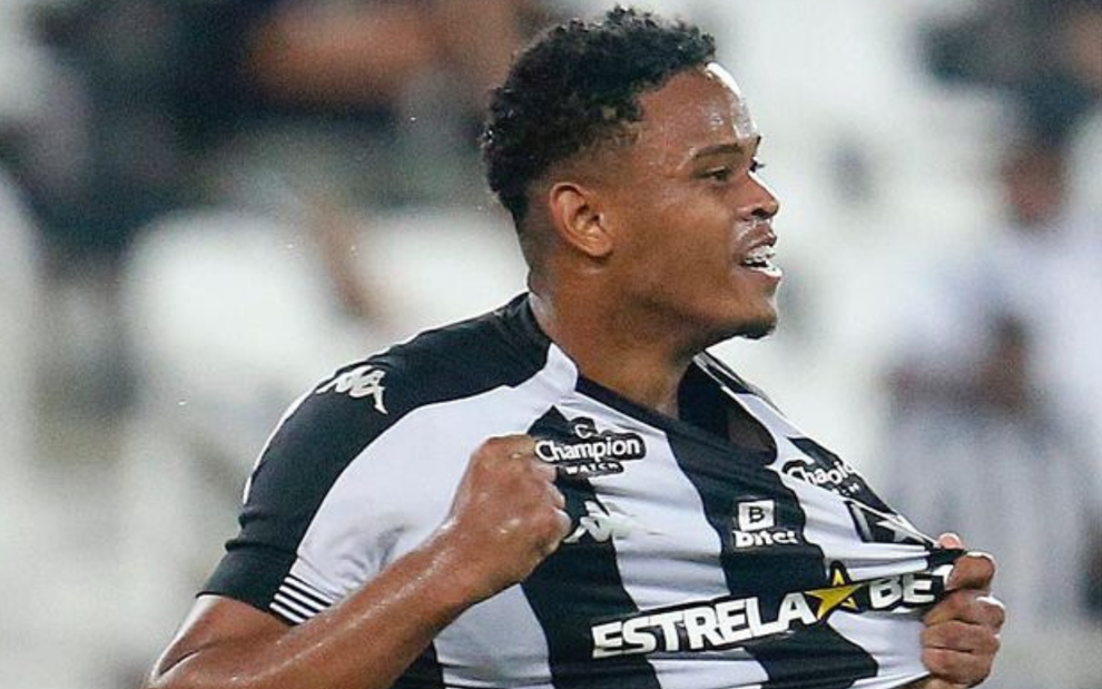 Lucas Mezenga, do Botafogo, comemorando puxando o escudo do uniforme listrado preto e branco