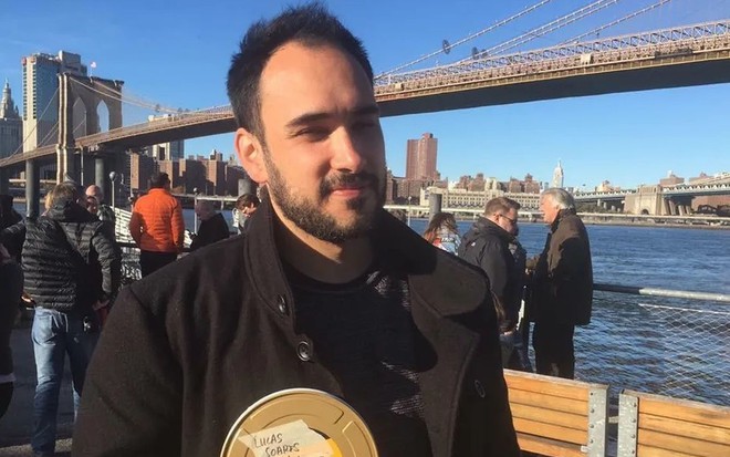 Lucas Villamarim está em Nova York usando um casaco preto sob uma blusa da mesma cor